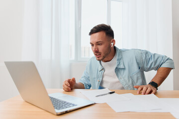 Fototapeta premium Crazy angry irritated handsome stylish young businessman scream at laptop hates computer crash operation problems in office. Copy space for ad. Remote Job, Technology And Career Profession Concept