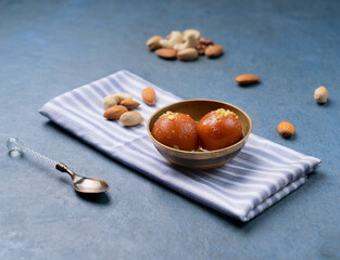 Gulab jamun with nuts served in a dish isolated on napkin side view on dark background indian sweet