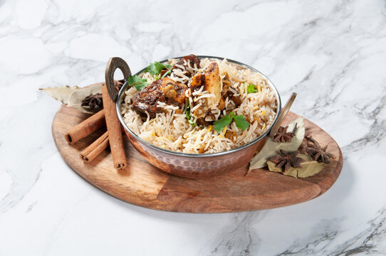 Lamb Shank Biryani with raita served in a dish isolated on wooden board side view on dark background