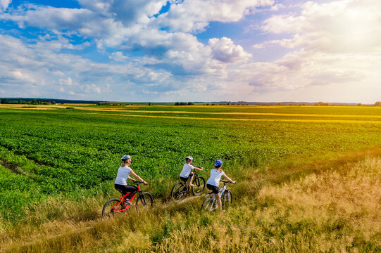 Healthy lifestyle - teenage girl and boy whith mother cycling. family on bike ride outdoors at sunset. active family sport and fitness together. drone photo