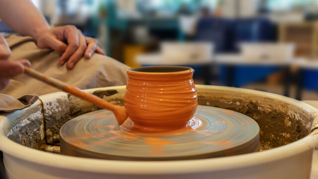 Potter coloring ceramic pot on a Potter's wheel at workshop. Hobbies, craft and handwork. Teaching pottery on a potter's wheel. Healthy free time. Selective focus