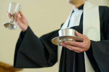 Catholic priest holding cups with wine and unleavened bread symbolizing flesh and blood of Savior...