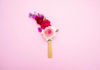 brush and rose flowers on pink paper background, top view