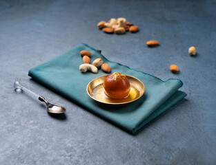 Gulab jamun with nuts served in a dish isolated on napkin side view on dark background indian sweet