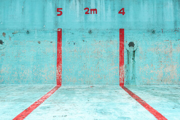 Focus on a piece of an abandoned swimming pool in a bright blue colour with red stripes. The lanes...