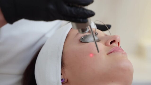 Cosmetologist providing facial skin therapy with YAG laser