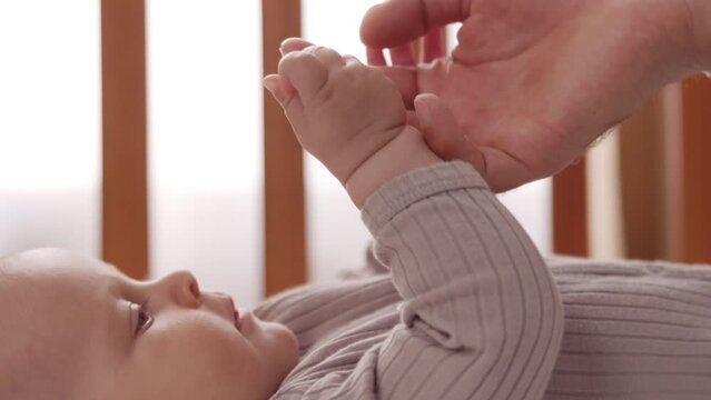 Close up shot of newborn little cute hand reaching for father's loving finger. Baby holding parents finger. Happy moment. Parentheses. Child. Slow motion