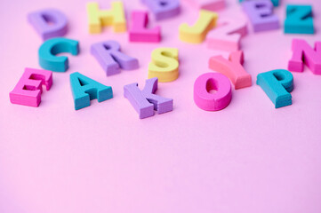 Fototapeta premium colorful wooden letters on pink background with copy space