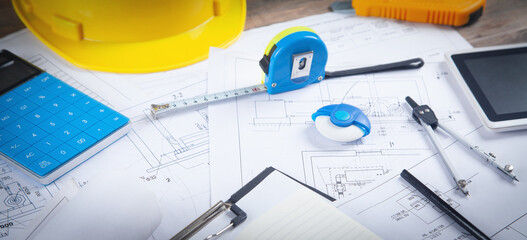 Architects workplace with measure tape, architectural project plan and other objects.