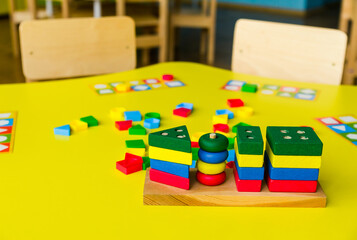 Colorful wooden blocks on yellow table. Creativity toys. Children building blocks. Geometric shapes - circle, triangle, square, rectangle. The concept of logical thinking.