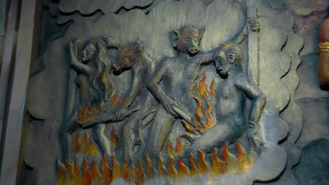 A painting on a wall in a Buddhist temple depicting hell. Torment of sinners. Servants of hell burn souls with fire in hell.