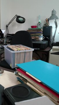 Vertical dolly across hopelessly cluttered home office desk with piles of files.