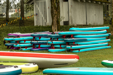 Fototapeta na wymiar Multicolored SUP boards. Station for active recreation and water sports, inflatable boards