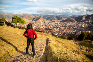 Woman looking from above the city of Cusco on a cloudy sky day, Peru