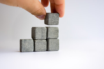 Hand laying stone cubes in the form of a stepped staircase shape.