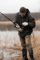 fisherman adjusts reel on spinning rod....