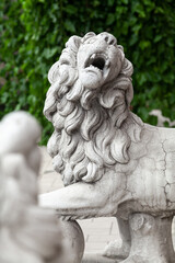 Ancient sculpture of lion with ball in the summer garden....