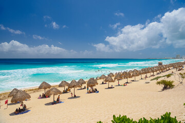 Umbrelas on a sandy beach with azure water on a sunny day near Cancun, Mexico