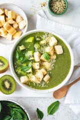 Vegan green smoothie bowl with toppings banana kiwi and hemp seeds