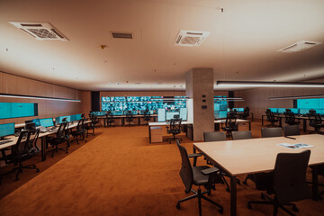 Empty interior of big modern security system control room, workstation with multiple displays, monitoring room with at security data center Empty office, desk, and chairs at a main CCTV security data