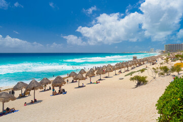 Fototapeta na wymiar Umbrelas on a sandy beach with azure water on a sunny day near Cancun, Mexico