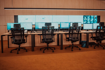 Empty interior of big modern security system control room, workstation with multiple displays, monitoring room with at security data center Empty office, desk, and chairs at a main CCTV security data