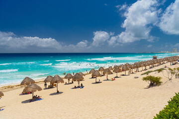 Fototapeta na wymiar Umbrelas on a sandy beach with azure water on a sunny day near Cancun, Mexico