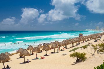 Umbrelas on a sandy beach with azure water on a sunny day near Cancun, Mexico