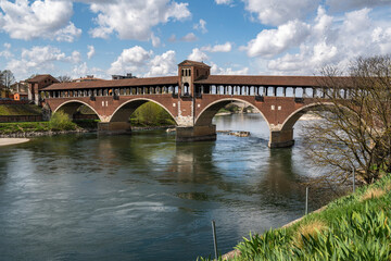 The Ponte Coperto (Covered Bridge) in Pavia, a brick arch bridge over the Ticino River, Lombardy, Italy - obrazy, fototapety, plakaty