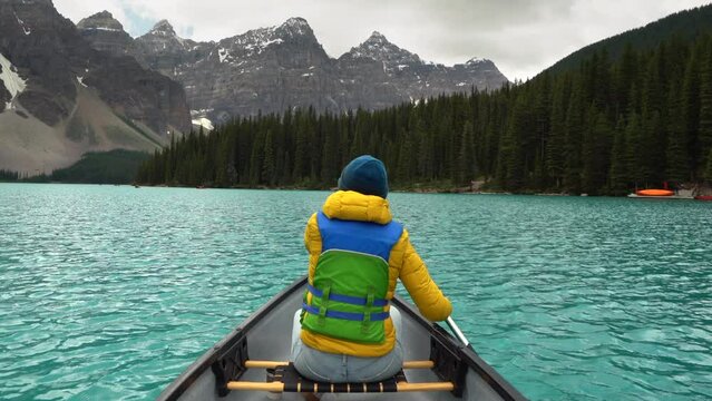 Female tourist paddling a canoe on Moraine Lake during summer in Banff National Park, Alberta, Canada.
