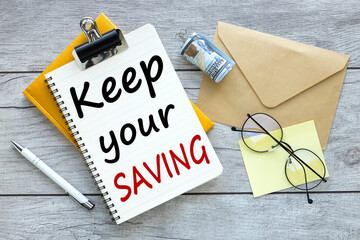 KEEP YOUR SAVINGS text on paper on two notebooks