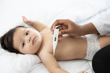 Obraz na płótnie Canvas doctor measuring baby's temperature on bedroom