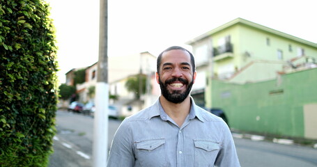 Casual Happy hispanic man in 40s smiling at camera outside in urban street