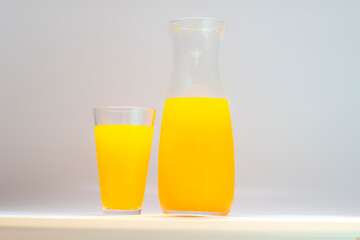 orange juice in glass cup and jug, different angles on white background