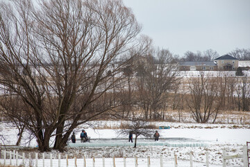 Amish men harvesting ice on a pond in winter in Holmes County, Ohio