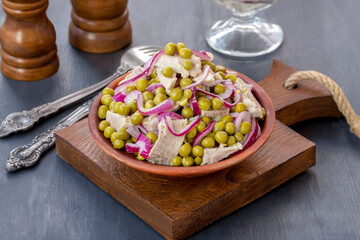 Green pea salad with braised pork, red onion and lemon and olive oil dressing served in a bowl on dark Wooden background. 