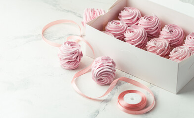 White gift box full of pink berry marshmallow. Zefir dessert with red currant mousse on the white marble background