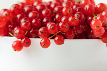 Red currant berries with green leaves isolated on the white background. Fresh summer berries