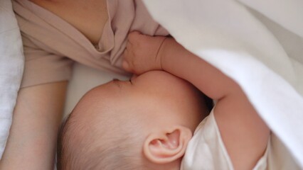 Obraz na płótnie Canvas Baby fall asleep holding mom on bed
