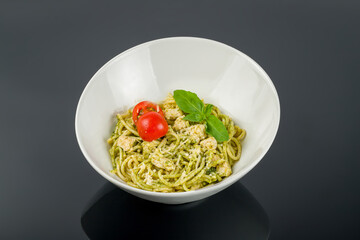 Pasta with chicken and pesto sauce on black with reflection