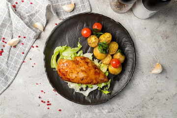 Grilled chicken Breasts with mini potatoes on black plate