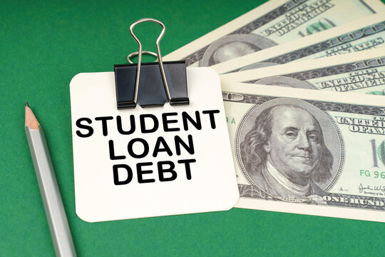 On a green surface, a pen, dollars and paper with the inscription - Student loan debt