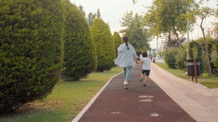 Back view of preschooler and mom running along the alley