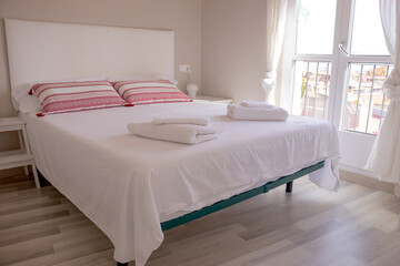 Fototapeta na wymiar Hotel or hostel bedroom with white king size bed, towels and balcony