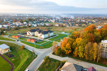 Fototapeta na wymiar Aerial view of school, college or kindergarten building with big yard among autumn trees on rural landscape background