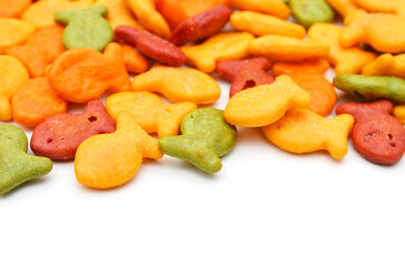 A scattering of yellow fish crackers on white background 