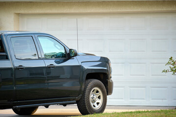 Car parked in front of wide garage double door on concrete driveway of new modern american house