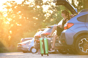 Young woman with suitcase bag waiting near her car. Travelling and vacations concept