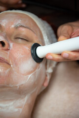 Mature woman with green eyes receiving a facial treatment