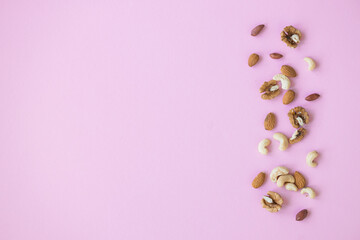 Fototapeta na wymiar Creative layout made of hazelnut nuts, almonds, walnut, peanut, cashew on pink background. Flat lay. Food concept.